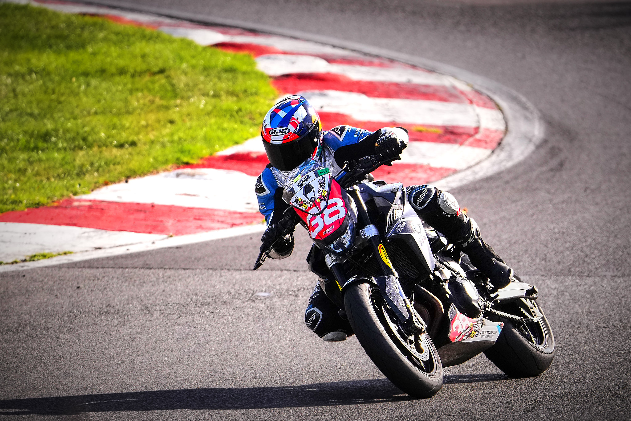 Rider in a blue helmet leans a black number 68 naked motorbike through a corner at Brands Hatch